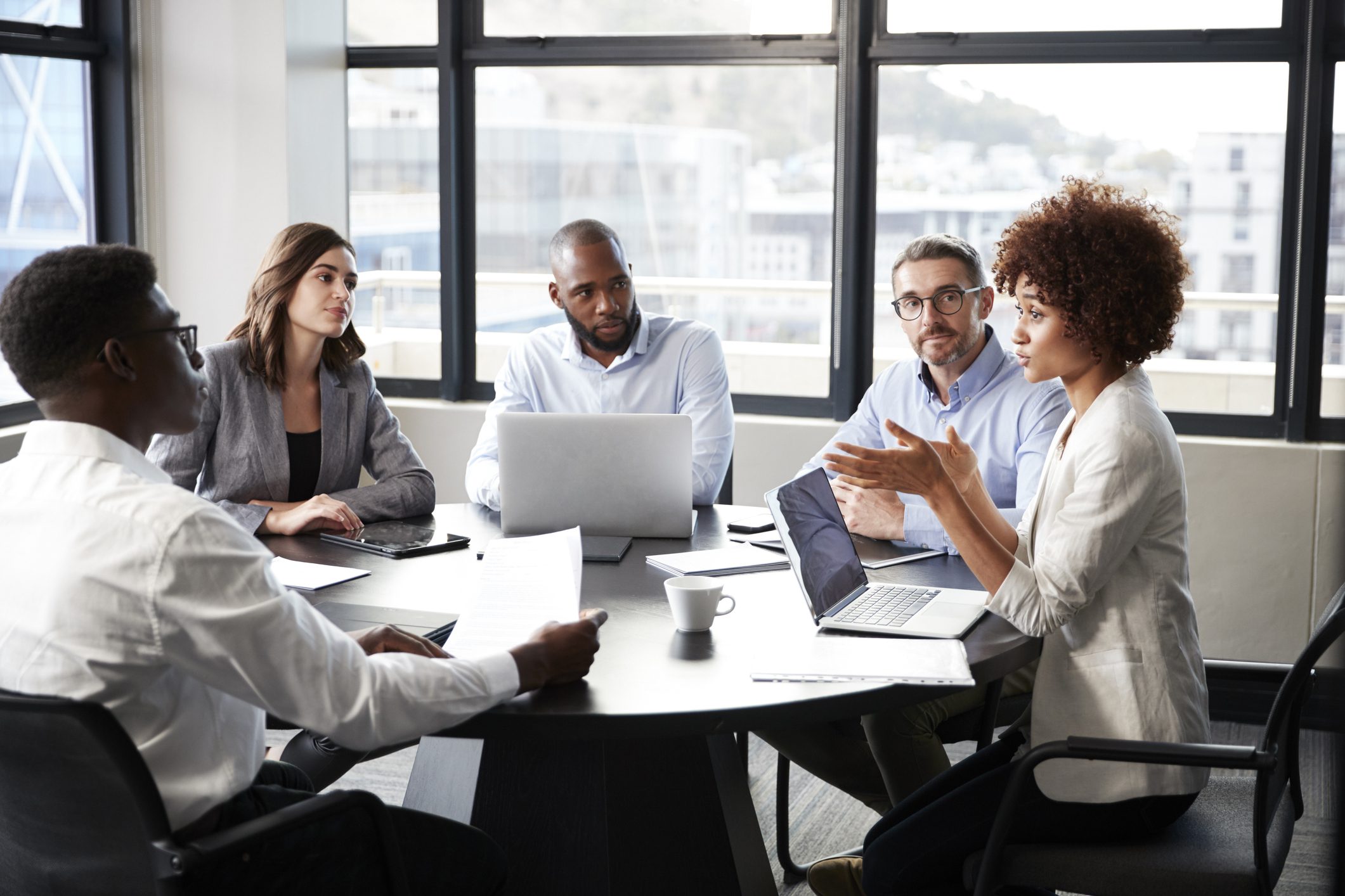 Millennial black businesswoman addressing colleagues at a corporate business meeting, close up Team meeting with laptops in modern office.